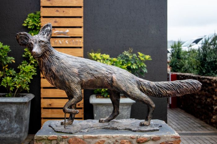 Bronze fox sculpture positioned on a stone pedestal in a courtyard garden - demonstrating how animal-themed art creates visual punctuation and focal moments in landscape design.
