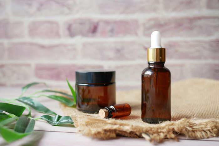 Amber glass bottles and jars with natural essential oils on burlap cloth, representing eco-friendly and safe homemade cleaning solutions.