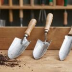 Three garden trowels with different blade shapes placed on a workbench, showing common trowel types used for planting, transplanting, and soil work